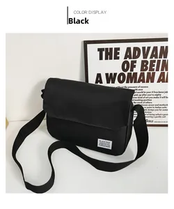 Detail of minimalist black messenger bag with white woven label and adjustable strap
