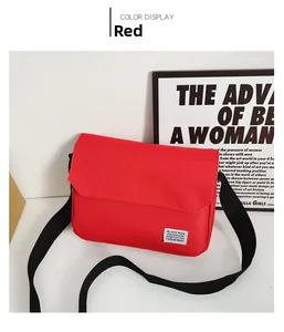 Detailed shot of red canvas messenger bag with adjustable black strap and woven brand tag