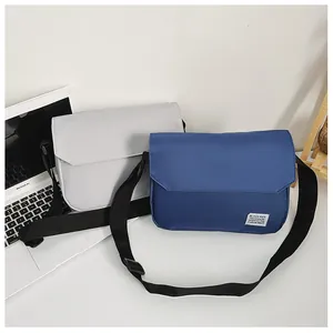 Minimalist canvas messenger bags in grey and blue with adjustable straps and logo tags