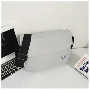 Detailed shot of a light grey canvas messenger bag with flap and black adjustable strap