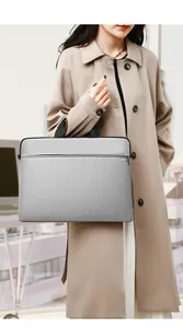 Close-up of lightweight grey waterproof laptop bag held by a model in office setting