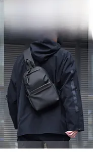 Male model wearing a sleek black waterproof chest bag in a modern urban industrial setting