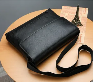 Detail of black lychee grain leather briefcase with adjustable nylon strap on a wooden desk