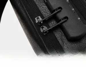Detailed macro view of the anti-theft combination lock and dual metal zippers on leather bag