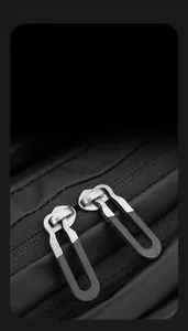 Close-up of smooth dual-way metal U-shaped zippers on a waterproof black messenger bag