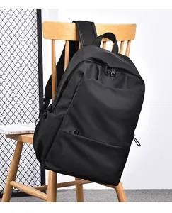 Detail of minimalist black backpack with adjustable drawstrings on a wooden chair