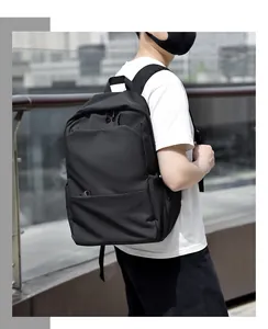 Outdoor view of a minimalist black backpack featuring multiple zipper compartments and side pockets