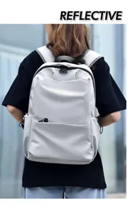 Close-up of light gray reflective backpack with dual zippers and adjustable side drawstring