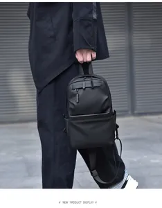Close-up of minimalist black water-resistant crossbody bag held by hand in urban setting