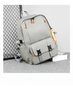 Detail of light grey backpack with black buckle and bright orange zipper pullers