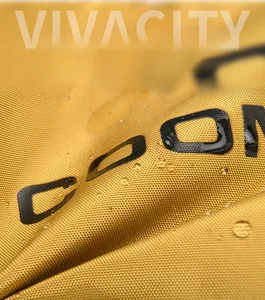 Gros plan du tissu jaune imperméable du sac de voyage avec des gouttelettes d'eau