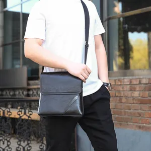 Men's black leather crossbody shoulder bag with flap closure shown on outdoor model