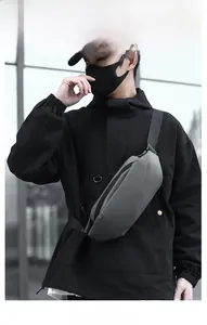 Close-up of matte grey water-resistant chest bag with adjustable black strap on model