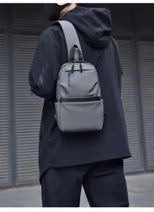 Waterproof grey men's crossbody bag shown on model against a modern urban wall background