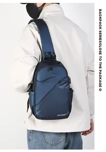 Détail des compartiments à glissière multicouches et logo sur un sac bandoulière bleu marine