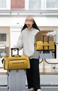 Détail du sac de voyage jaune montrant la sangle de fixation pour poignée de valise