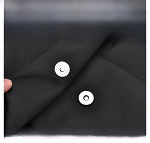 Close-up of silver magnetic buckle and durable black fabric texture on the backpack