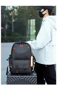 Close-up of black travel backpack with orange zippers placed on a textured suitcase