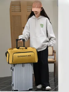 Sac de voyage jaune avec bandoulière monté sur la poignée d'une valise argentée