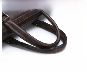 Detail of the thickened leather handle and metallic zipper on a dark brown briefcase