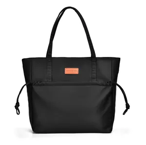 Detail view of black tote bag featuring side drawstrings and orange leather logo patch