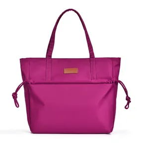 Detail of magenta tote bag showing drawstring pocket and leather brand patch on smooth fabric