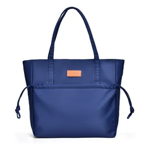 Detail of navy blue tote bag featuring front drawstring pocket and brand logo patch