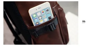 Détail de la poche latérale du sac à dos en cuir marron avec sangle et boucle pour téléphone