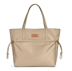 Detail of khaki nylon tote bag with drawstring front pocket and brown leather brand tag