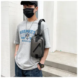 Detail view of a men's crossbody chest bag in dark grey with adjustable strap on a model