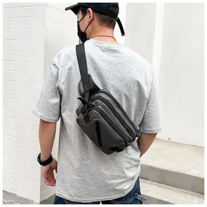 Rear view of dark grey-green nylon crossbody bag with multi-zipper layers and wide strap