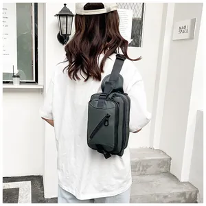 Outdoor shot of a durable nylon crossbody bag in dark green worn by a model from the back