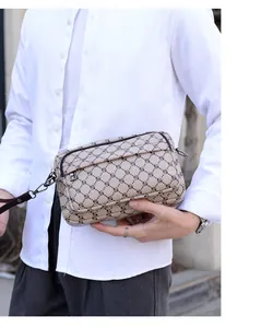 Détail du sac messager à carreaux montrant les fermetures éclair et la texture