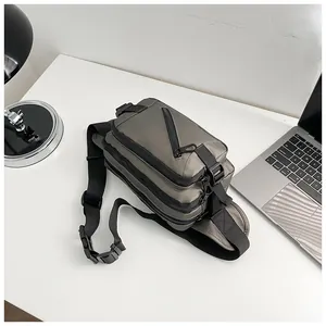 Detail of grey oxford fabric crossbody bag with multi-layer zippers on office desk