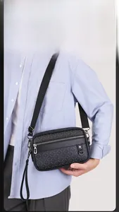 Detail of black crossbody bag with logo pattern, metal zipper, and adjustable strap