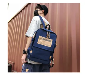 Close-up of a navy canvas backpack featuring a brown logo patch and durable zippers