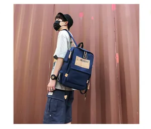 Detail view of navy canvas backpack with logo patch on industrial metal background