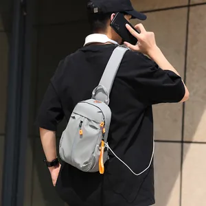 Gray crossbody chest bag for men with orange zipper details and USB charging port