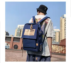 Detailed outdoor view of blue canvas backpack with brown leather patch and side pockets