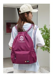 Detail of purple drawstring backpack featuring a white B logo and side mesh pockets