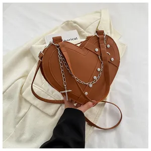 Detailed view of brown heart-shaped bag featuring silver studs and metal cross chain