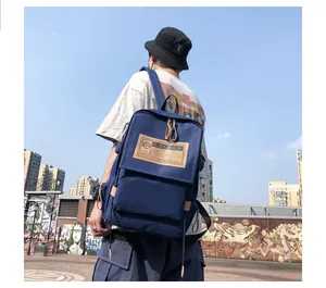 Detail of navy blue canvas backpack featuring dual zippers and branded patch in city setting