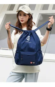 Detail of navy blue drawstring backpack with front zipper pocket and white brand logo