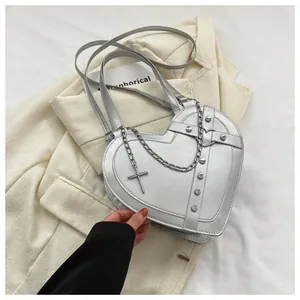 Detail view of silver heart bag featuring punk rivets, metal chains, and a cross pendant
