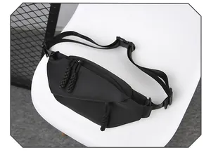 Detail of black sports chest bag with dual zippers and durable woven strap on chair