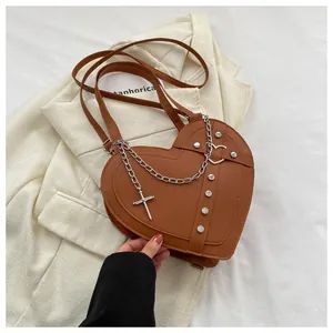 Detail of heart-shaped brown leather bag with silver rivets and cross chain on a blazer