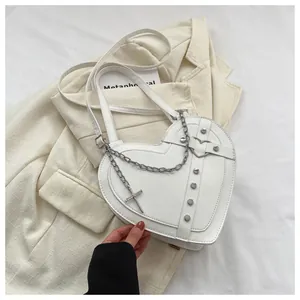Detailed close-up of white heart-shaped bag with punk rivets and silver cross chains