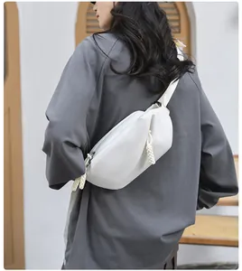 Close-up of minimalist white PU leather crossbody bag with braided zipper pull detail
