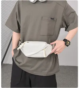 Detail of cream pleated waist bag featuring woven zipper pull and adjustable black nylon strap