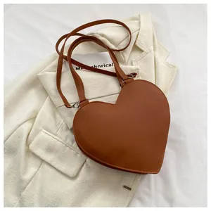 Detail shot of heart-shaped brown PU leather crossbody bag with silver hardware on blazer